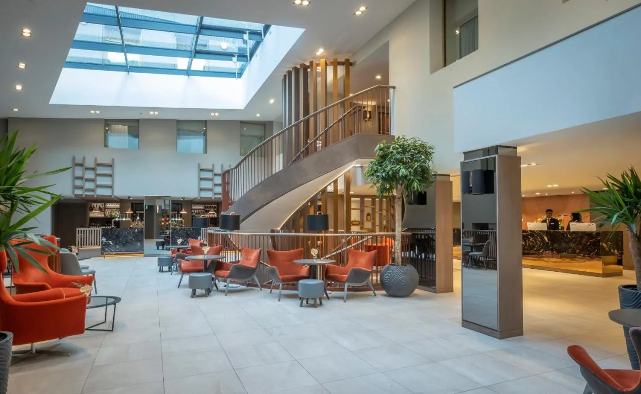 a lobby with orange chairs and a staircase at Clayton Hotel Bristol City in Bristol