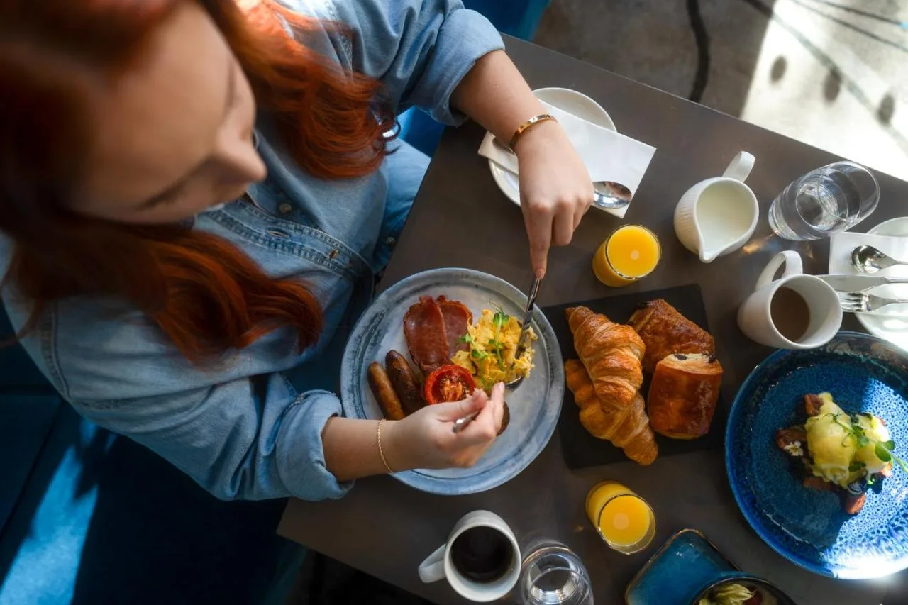 a woman sitting at a table with a plate of food at Clayton Hotel Bristol City in Bristol